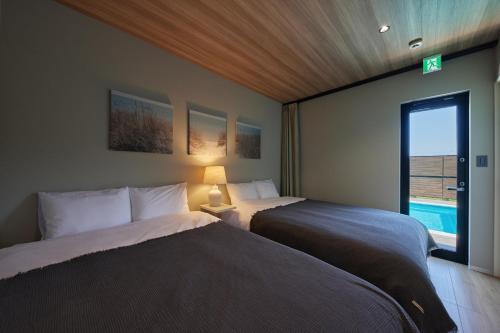 a bedroom with two beds and a window with a pool at POOL VILLA 莉-rei- in Takashima