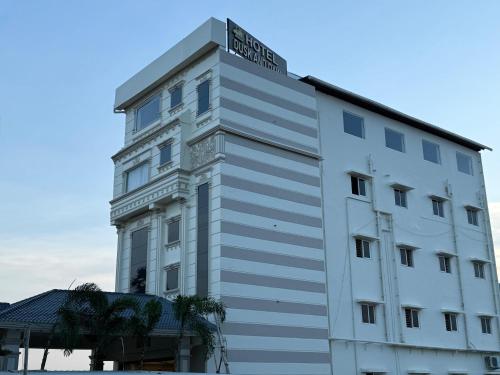 a white building with a sign on the top of it at Hotel Dusk and Dawn in Rāmeswaram