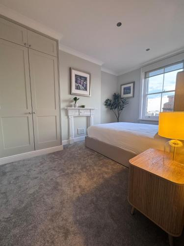 a bedroom with a large bed and a fireplace at Newly Furnished 1 Bed Flat in Wimbledon Village in London