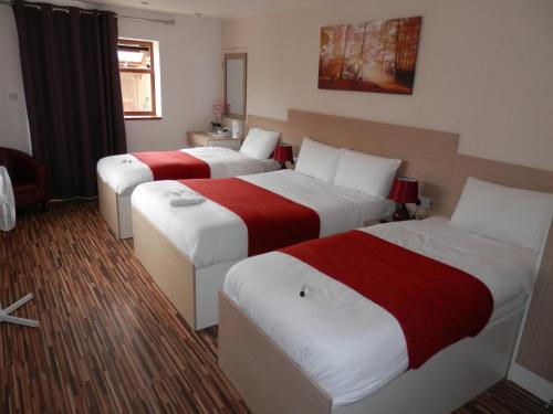 a hotel room with two beds with red and white sheets at Heathrow Travellers Hub in Hounslow