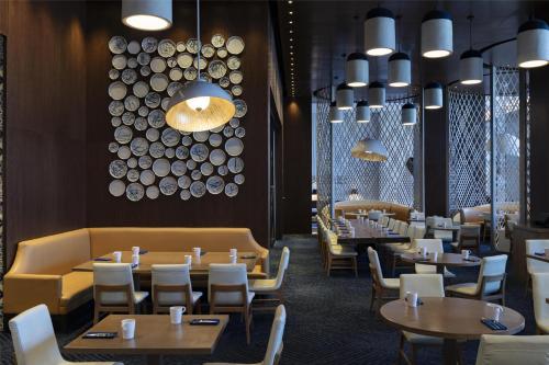 a restaurant with tables and chairs and a chandelier at Hilton Guadalajara Midtown in Guadalajara