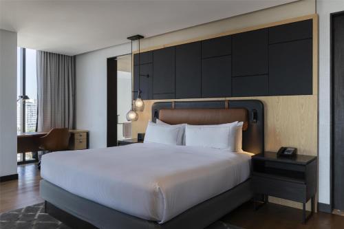 a bedroom with a large white bed and a desk at Hilton Guadalajara Midtown in Guadalajara