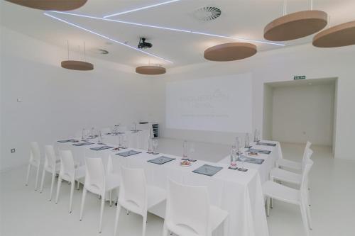 a long white room with white tables and white chairs at Higuerón Hotel Curio Collection by Hilton in Fuengirola
