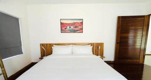 a bedroom with a white bed with a picture on the wall at Ploythai Villa Koh Phangan in Haad Pleayleam