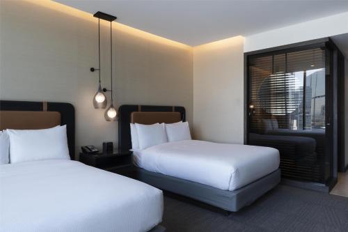 a hotel room with two beds and a balcony at Hilton Guadalajara Midtown in Guadalajara