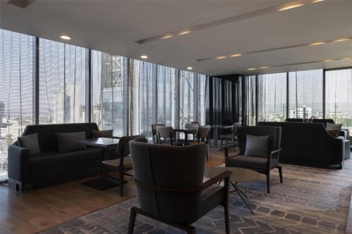 a lobby with chairs and tables and large windows at Hilton Guadalajara Midtown in Guadalajara