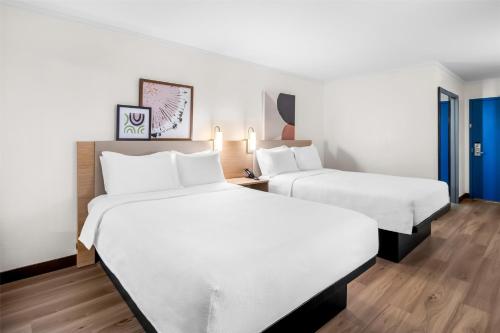 two beds in a hotel room with white sheets at Spark by Hilton Roanoke Civic Center in Roanoke