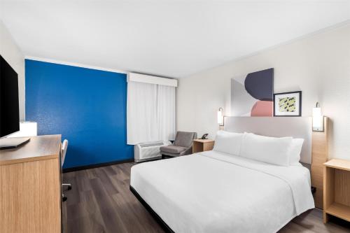 a hotel room with a white bed and a blue wall at Spark by Hilton Roanoke Civic Center in Roanoke