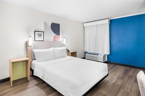 a bedroom with a white bed and a blue wall at Spark by Hilton Roanoke Civic Center in Roanoke