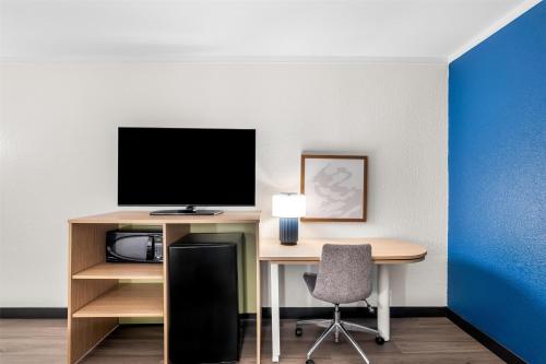 a room with a desk with a computer and a tv at Spark by Hilton Roanoke Civic Center in Roanoke