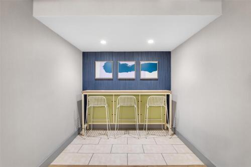 a bar in a room with two chairs and two windows at Spark by Hilton Roanoke Civic Center in Roanoke