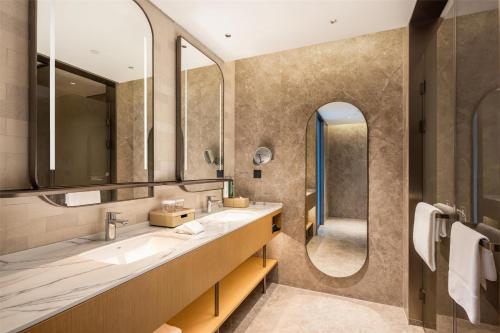 une salle de bain avec deux lavabos et deux miroirs dans l'établissement Hilton Garden Inn Olympic Sports Center Jinan, à Jinan