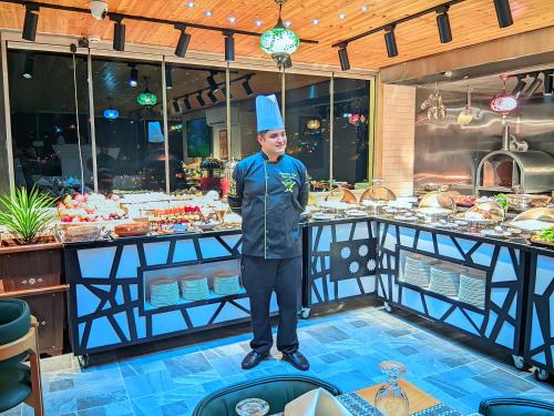 a man wearing a chef hat standing in front of a buffet at Petra Bermudez Hotel in Wadi Musa