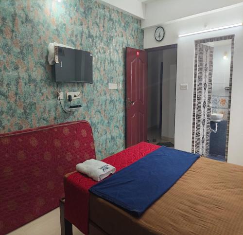 a bedroom with a bed and a tv on the wall at TNV Residency in Pūrnānkuppam