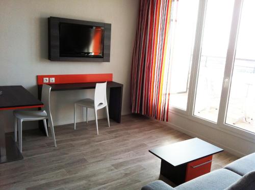 a living room with a desk and a tv on the wall at Adonis Paris Sud in Chevilly-Larue