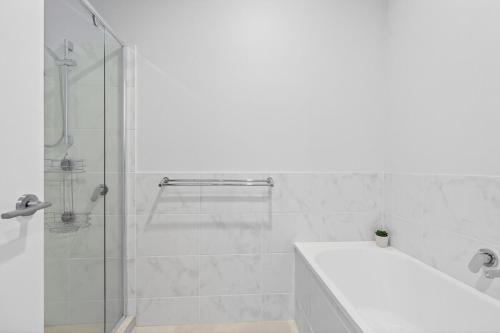 a white bathroom with a shower and a bath tub at Waterside in Victor Harbor