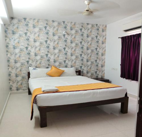 a bedroom with a bed with a floral wallpaper at TNV Residency in Pūrnānkuppam
