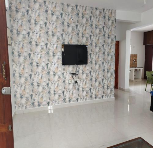a living room with a tv on a wall at TNV Residency in Pūrnānkuppam