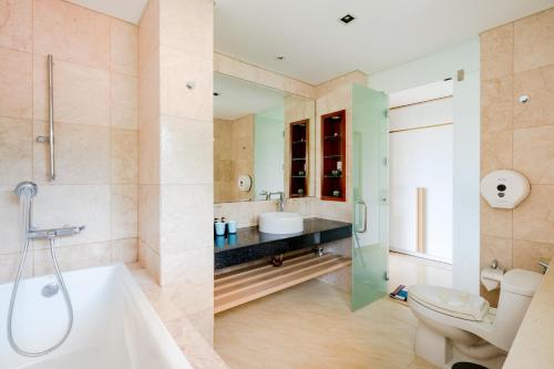 a bathroom with a tub and a toilet and a sink at Ocean Villas Da Nang in Danang