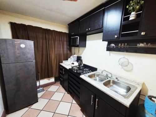 a kitchen with black cabinets and a stainless steel sink at Departamento acogedor y céntrico in Oaxaca City