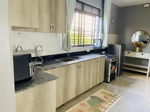 a kitchen with wooden cabinets and a sink and a refrigerator at Komie Stay Bunga in Kampala