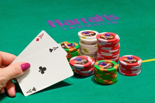 a person holding a pair of poker cards and poker chips at Harrah's Laughlin Beach Resort & Casino in Laughlin