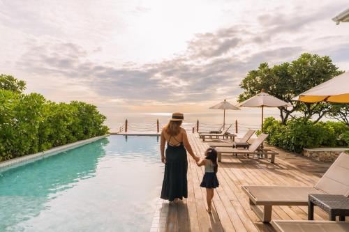 a woman and a child standing next to a swimming pool at De Chaochom Hua Hin in Hua Hin