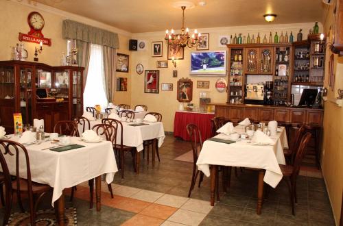 a restaurant with white tables and chairs in a room at Lévay Villa Hotel in Miskolc