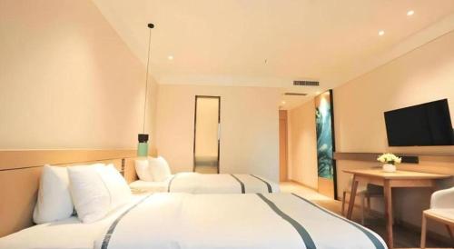 a hotel room with two beds and a television at City Comfort Inn Wuhan Wansongyuan Wangjiadun East Metro in Wuhan