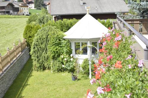 a gazebo in a garden with flowers at Pension Panorama in San Lorenzo di Sebato