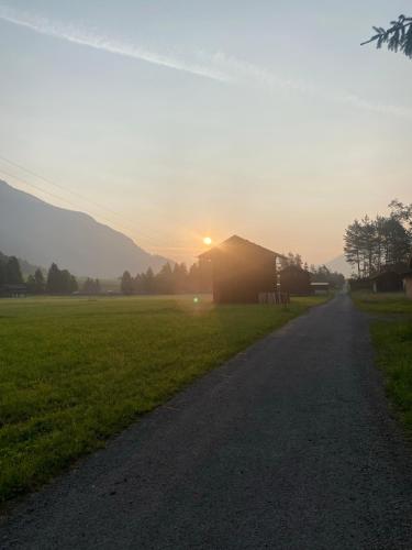 a road leading to a field with the sun setting at Ferienwohnungen LODGE-B in Weissenbach am Lech