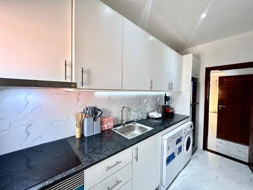 a kitchen with white cabinets and a sink at Comfort zone in Futungo de Belas