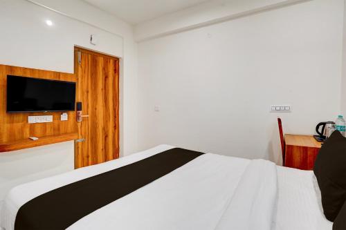 a bedroom with a bed with a television on the wall at Super Townhouse Marathahalli KLM Fashion Mall Formerly Hotel Avenue in Bengaluru