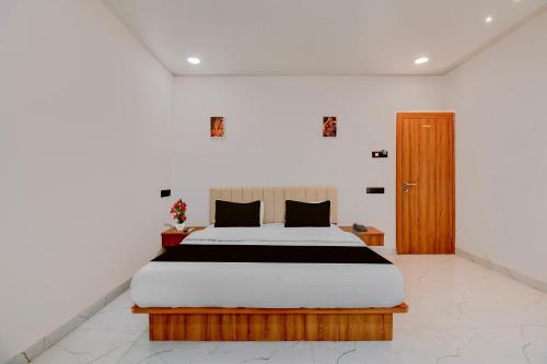 a bedroom with a bed and a wooden door at Super Collection O Aurangabad Shendra MIDC Formerly Prayag Inn in Karmād