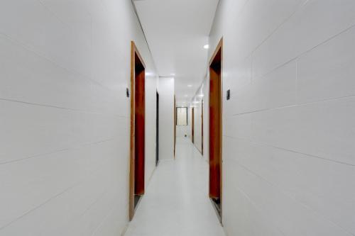 an empty hallway with white walls and wooden doors at Super Collection O Aurangabad Shendra MIDC Formerly Prayag Inn in Karmād