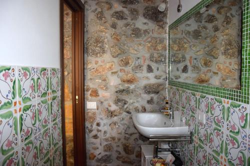 a bathroom with a sink and a stone wall at La Casa del Geko in Cefalù