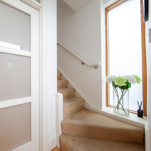 a staircase with a vase of flowers in a window at Light Filled 2BD Home with Sea Views Baldoyle in Baldoyle