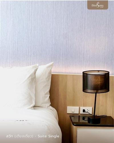 a bedroom with a bed and a table with a lamp at โรงแรมบลอสซั่ม เพชรบูรณ์ Blossom Hotel in Phetchabun