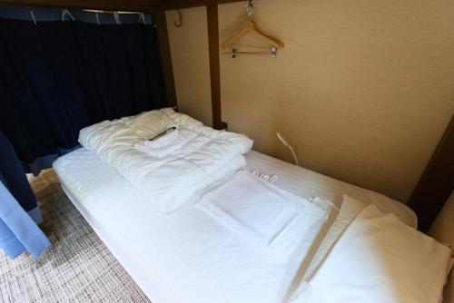 a bed with white sheets on it in a room at KOMOREBI HOSTEL-your cozy place- in Takayama