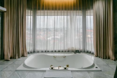 a bath tub in a room with a large window at Horison Ultima Bandung in Bandung