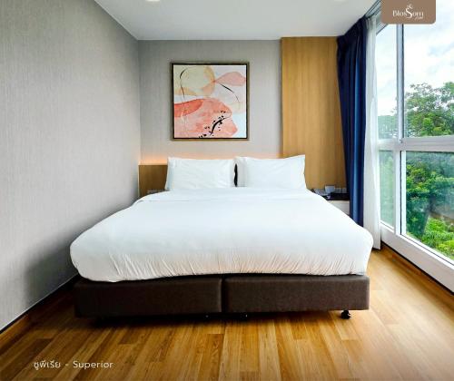 a bedroom with a large white bed with a window at โรงแรมบลอสซั่ม เพชรบูรณ์ Blossom Hotel in Phetchabun