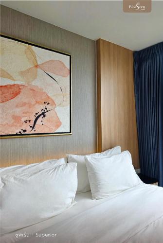 a bed with white pillows in a hotel room at โรงแรมบลอสซั่ม เพชรบูรณ์ Blossom Hotel in Phetchabun