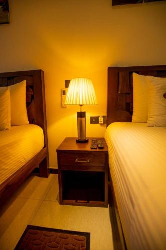 a bedroom with two beds and a lamp on a night stand at Airport Faith Hotel in Katunayake