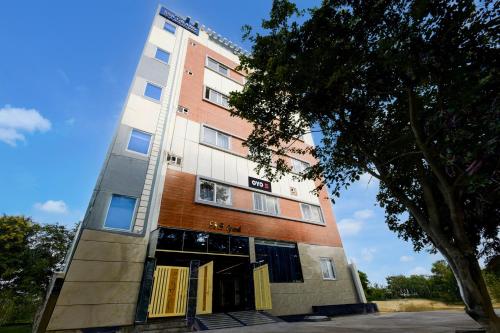 a tall building with its doors open next to a tree at S S B Grand in Ibrāhīmpatan