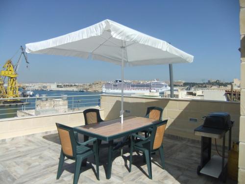 una mesa y sillas con una sombrilla en el techo en Senglea Apartments, Triq il-Kurcifiss, L-Isla, en Senglea