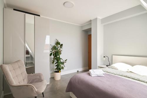 a bedroom with a bed and a chair and a plant at LeoApart in Wrocław