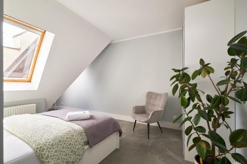 a bedroom with a bed and a chair and a plant at LeoApart in Wrocław