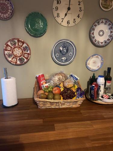 a basket of fruit on a table with plates on the wall at Country Cosy Cottage in Bailieborough