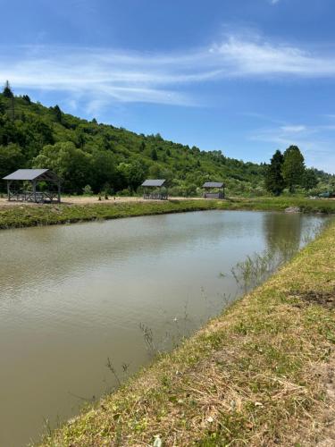 a river with two gazebos on the side of it at В тиші Келечина in Kelechin