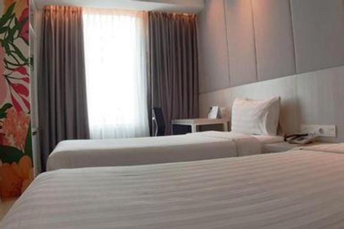 a hotel room with two beds and a window at PARK HOTEL Cawang Jakarta in Jakarta
